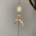 Gold pendant with sun and arch design on a chain against a gray background